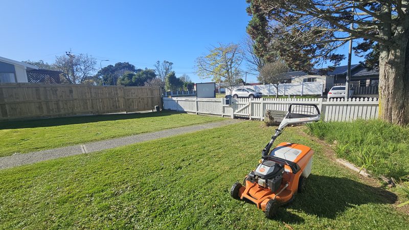 Front yard with a white picket fence and mower on the lawn