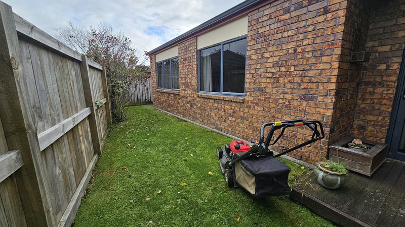 Narrow striped backyard lawn beside a brick home