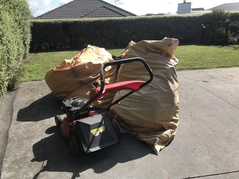 Bundled yard-waste bags and mower after a cleanup